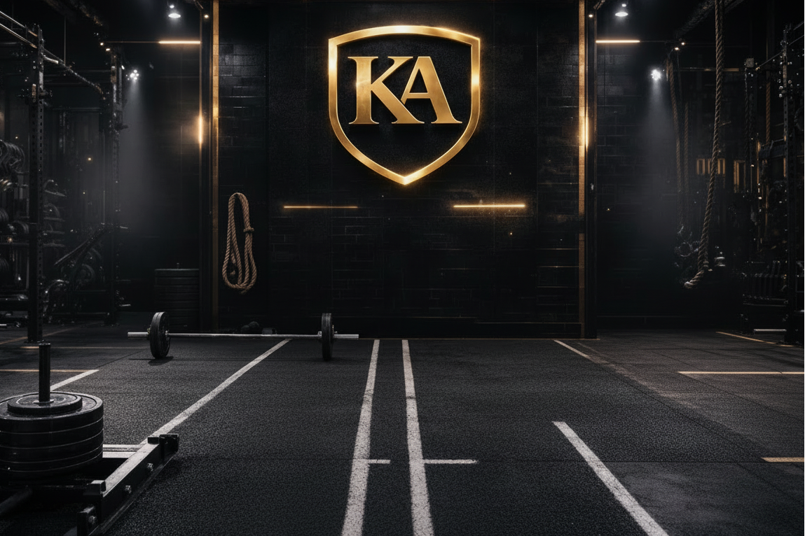 Group of people exercising with gym equipment in a darkly lit gym, featuring the KA logo.